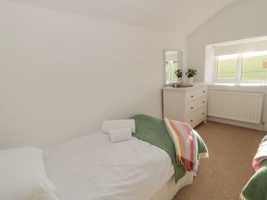 A bedroom with a single bed a chest of drawers a mirror and a window at Little Haven in Bamburgh