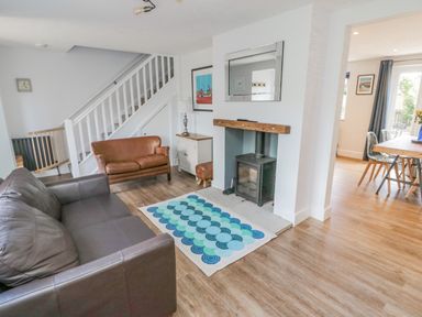 A living room with two sofas a wood burning stove and a rug at 3 St Cuthberts Garth in Bamburgh