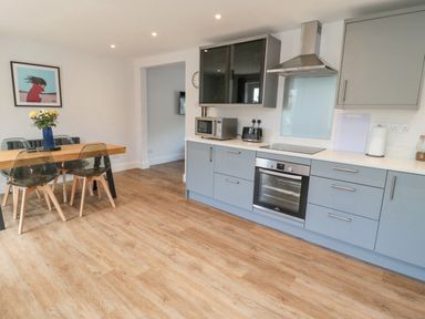 A kitchen with blue cabinets, an oven, a microwave, a toaster, and a dining table with four chairs at 3 St Cuthberts Garth in Bamburgh