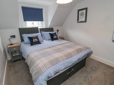 A bedroom with a double bed blue bedding and pillows beside two bedside tables with lamps at 3 St Cuthberts Garth in Bamburgh