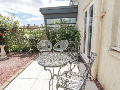 An outdoor patio with ornate metal table and chairs two wire framed chairs and plants at 3 St Cuthberts Garth in Bamburgh
