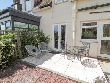 A small patio area with two modern chairs and a metal table with two chairs outside a house at 3 St Cuthberts Garth in Bamburgh