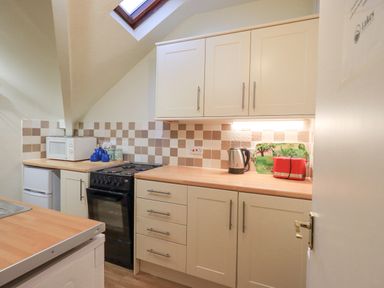 A kitchen with cream cabinets a black oven a microwave a kettle a red toaster and a skylight at Windermere Crescent in Windermere