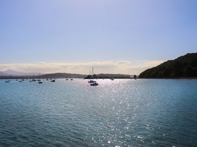 A body of water with boats and hills in the background at Bethania in Llangoed near Beaumaris