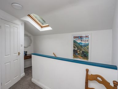 A hallway with a skylight a framed railway poster a wooden chair and a small desk at Bethania Llangoed near Beaumaris
