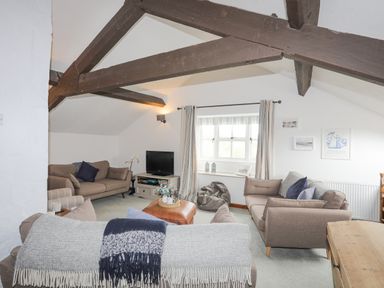 A living room with sofas a television and exposed wooden beams at Bethania in Llangoed near Beaumaris