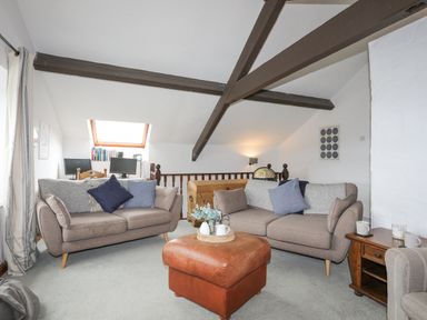 A living room with two sofas a leather ottoman and wooden side table with cups and candles at Bethania Llangoed near Beaumaris
