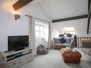 A living room with two sofas a television on a stand and a leather ottoman at Bethania in Llangoed near Beaumaris