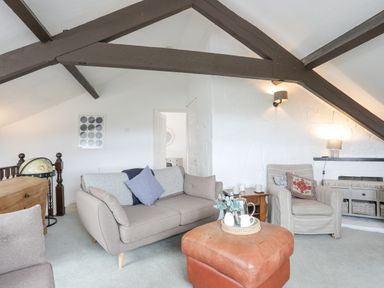 A living room with sofas a leather ottoman and wooden beams at Bethania in Llangoed near Beaumaris