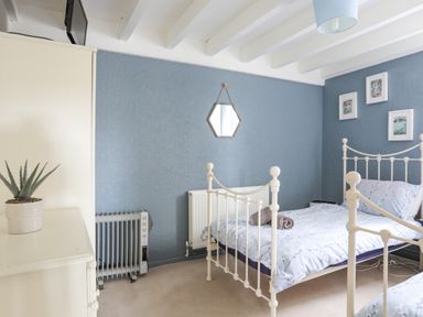 A bedroom with two metal framed beds a dresser with a plant on it and framed pictures on the wall at Bethania in Llangoed near Beaumaris
