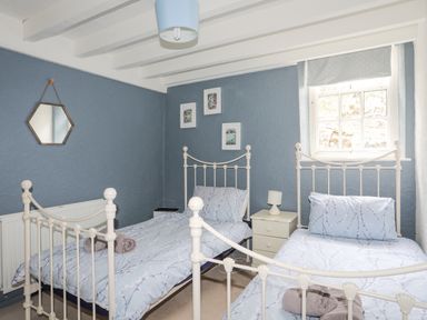 A bedroom with two single beds a bedside table a lamp and a window at Bethania in Llangoed near Beaumaris