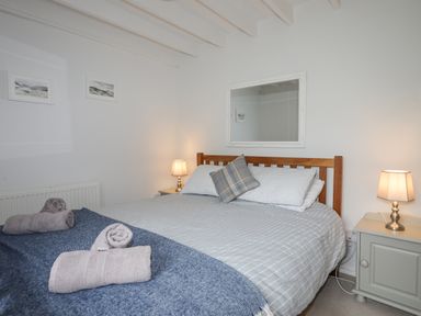A bedroom with a wooden bed frame blue blanket gray pillows bedside tables and lamps at Bethania in Llangoed near Beaumaris