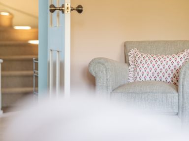 A grey armchair with a floral pillow next to a white door with black knobs at Cunsey Mill House Cunsey near Hawkshead