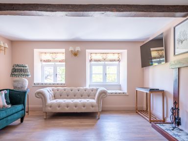 A living room with beige sofa green armchair and wall mounted tv at Cunsey Mill House Cunsey near Hawkshead