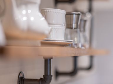 A wooden shelf with white ceramic cups and metal coffee makers mounted on a wall at Cunsey Mill House Cunsey near Hawkshead