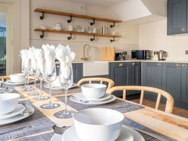 A kitchen with a dining table set with white bowls plates and glasses at Cunsey Mill House Cunsey near Hawkshead