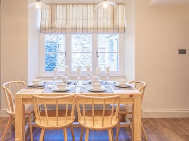 A dining table with place settings for six under a window with striped blinds at Cunsey Mill House Cunsey near Hawkshead