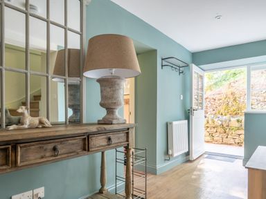 An entryway with a wooden table holding a lamp and a dog figurine in front of a large mirror at Cunsey Mill House Cunsey near Hawkshead
