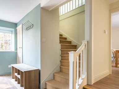 A hallway with carpeted stairs white railing wooden shelving unit and light blue walls at Cunsey Mill House Cunsey near Hawkshead