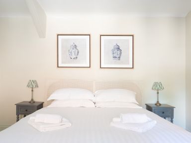 A bedroom with a double bed white linens towels on bed two bedside tables with lamps and two framed pictures on wall at Cunsey Mill House Cunsey near Hawkshead