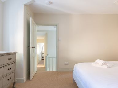 A bedroom with a bed and folded towels beside an open door showing a hallway at Cunsey Mill House Cunsey near Hawkshead