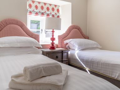 A bedroom with two single beds with pink headboards a wooden nightstand and a lamp at Cunsey Mill House Cunsey near Hawkshead