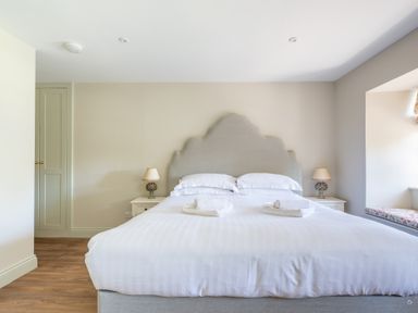 A bedroom with a large bed two bedside tables with lamps a built in wardrobe and a window seat at Cunsey Mill House Cunsey near Hawkshead