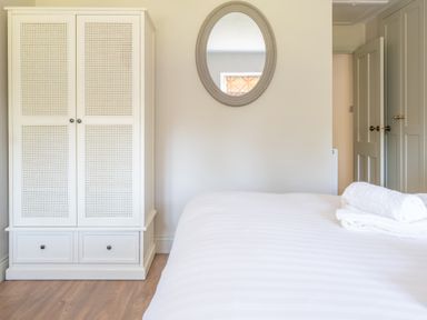 A bedroom with a white wardrobe an oval mirror and a bed with folded white towels at Cunsey Mill House Cunsey near Hawkshead