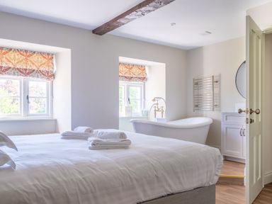 A bedroom with a bed and towels and a freestanding bathtub near windows at Cunsey Mill House Cunsey near Hawkshead