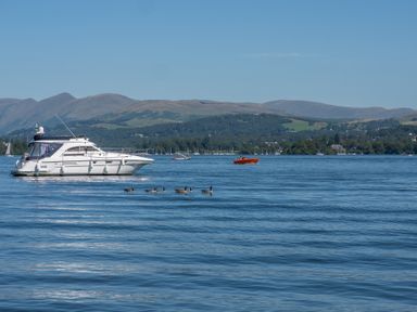 A lake with boats and ducks with hills in the background at Cunsey Mill House in Cunsey near Hawkshead