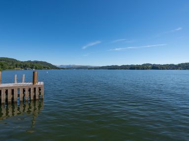 A wooden dock extending into a large lake with hills and trees in the background at Cunsey Mill House in Cunsey near Hawkshead