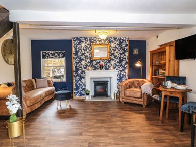 A sitting room with brown sofas a fireplace a wooden shelf and a small dining table at The Cheese Room in Stretton-On-Fosse