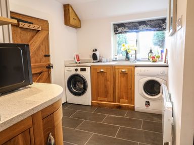 A utility room with a washing machine dryer wooden cabinets countertop and a window at The Cheese Room in Stretton-On-Fosse