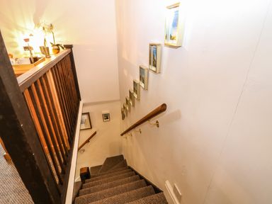A carpeted staircase with wooden handrails and framed pictures on the wall at The Cheese Room in Stretton-On-Fosse