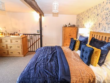 A bedroom with a bed with blue and brown bedding wooden furniture and wallpaper at The Cheese Room in Stretton-On-Fosse