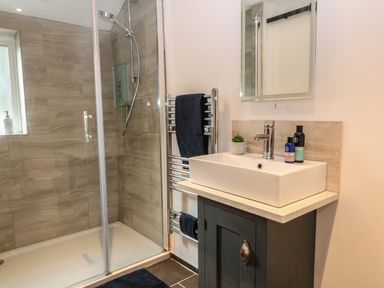 A bathroom with a glass enclosed shower a white sink on a dark cabinet and a towel rack at The Cheese Room in Stretton-On-Fosse