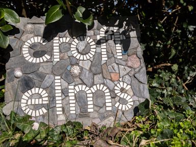 A mosaic stone sign with the words croft elms surrounded by green leaves and plants