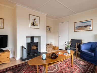 A living room with a fireplace television coffee table and chairs at Croft Elms in Trebetherick near Polzeath
