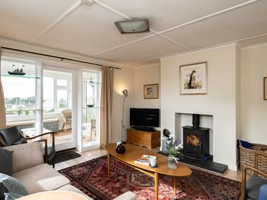 A living room with a wood burning stove a coffee table and a television at Croft Elms in Trebetherick near Polzeath