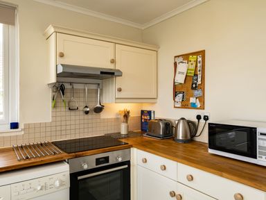 A kitchen with wooden countertops cabinets a microwave toaster kettle and cooking utensils at Croft Elms in Trebetherick near Polzeath