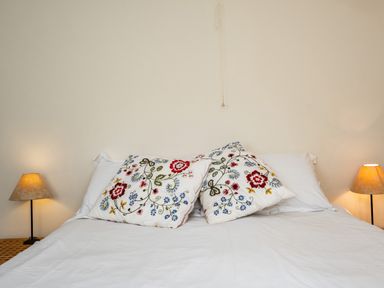 A bed with white sheets and two floral patterned pillows with matching lamps on each side at Croft Elms in Trebetherick near Polzeath