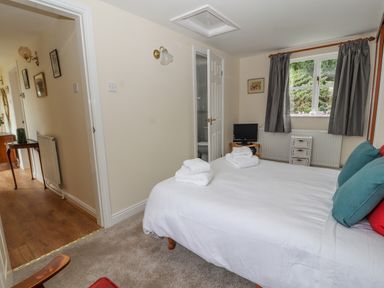 A bedroom with a bed and folded towels near a window and a doorway at Bryn Offa cottage in Holywell