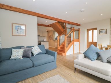 A living room with two sofas and wooden stairs leading to the upper floor at The Old Haberdashery in Swanage