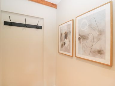 A wall with a black coat rack and two framed abstract artworks at The Old Haberdashery in Swanage
