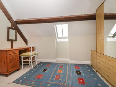 An attic room with a wooden desk and chair mirror skylight and a wardrobe with drawers at The Old Haberdashery in Swanage