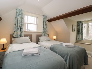 A bedroom with two single beds side by side and blue curtains at The Old Haberdashery in Swanage