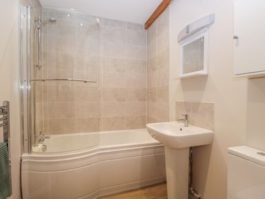 A bathroom with a bathtub shower combination sink and toilet at The Old Haberdashery in Swanage