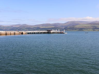 A pier extending into a body of water with mountains in the background at Bwthyn Dwyfor in Beaumaris