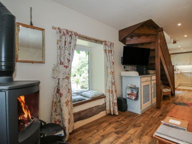A living room with a stove and staircase at Buzzards Breg in Builth Wells