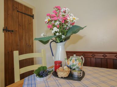 A kitchen table with flowers in a vase at Buzzards Breg in Builth Wells